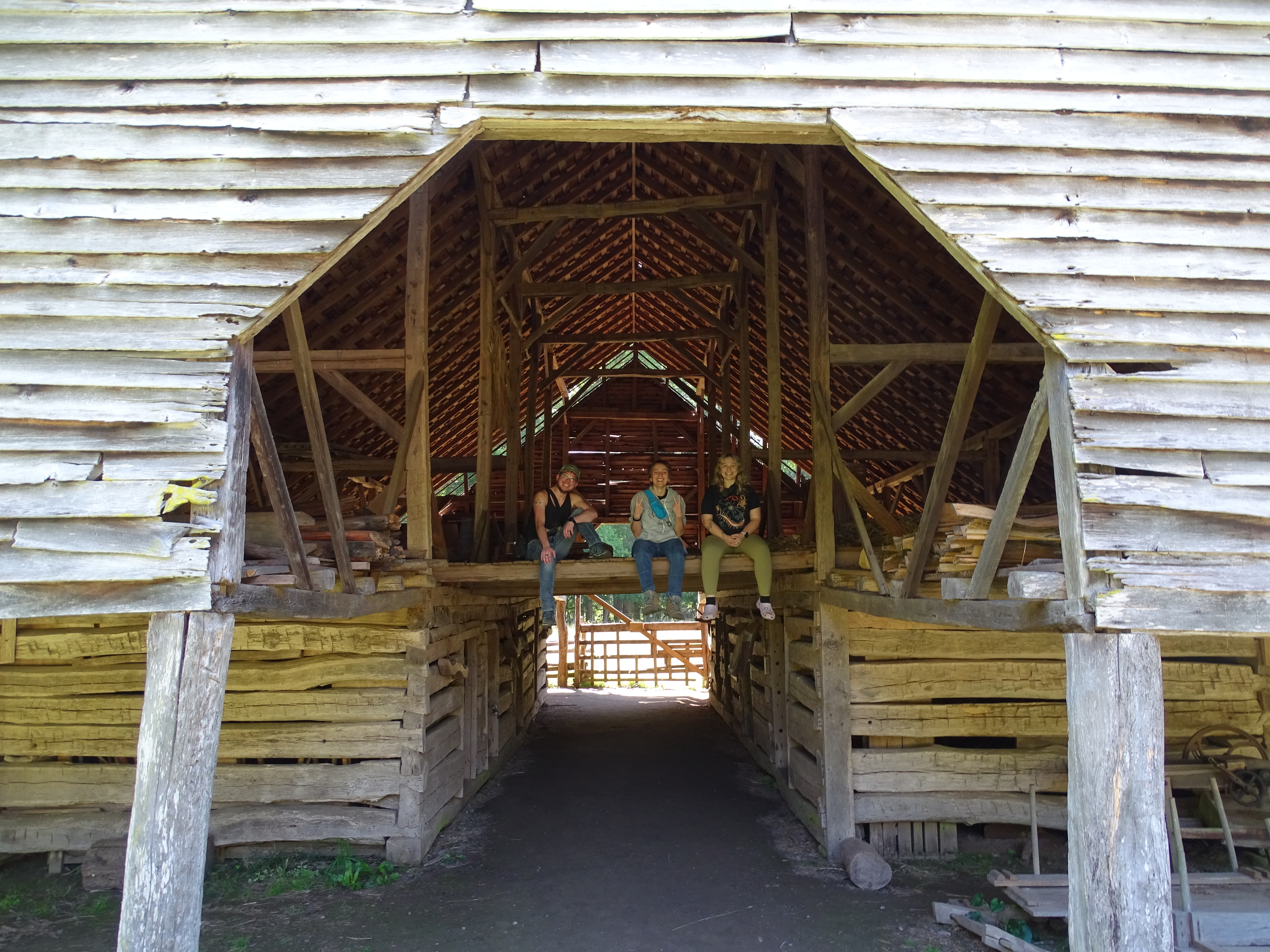 looking at a barn with a hay loft. All three people from the previous photograph are sitting in the hay loft and smiling at the camera.